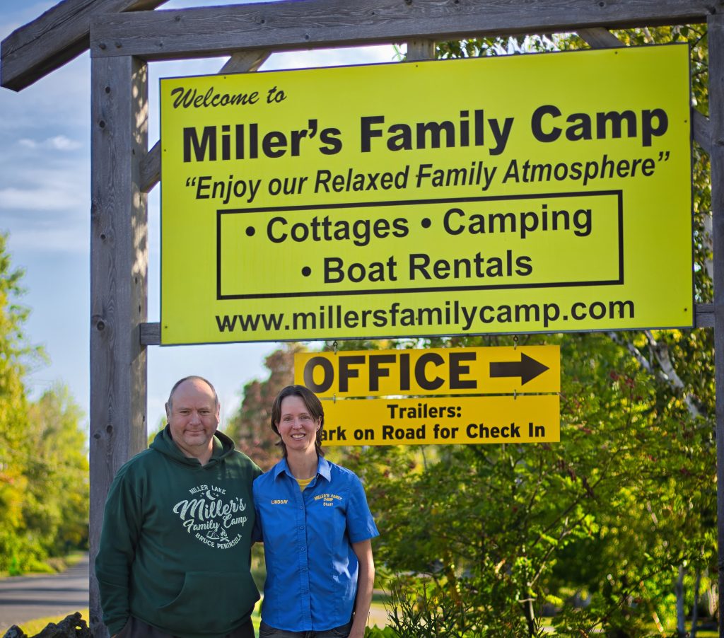 Owners standing in front of campground sign 